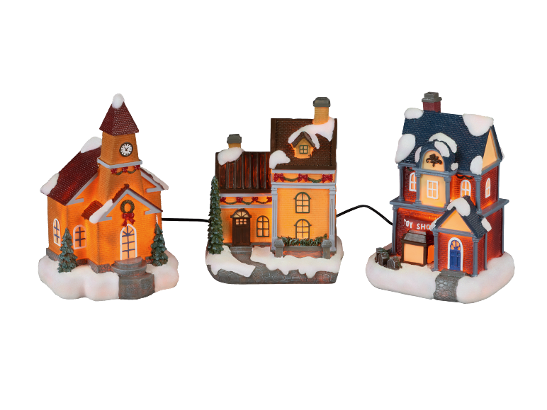 Set aus drei beleuchteten Weihnachtshäusern und einer Kirche mit Schnee, Girlanden und einem Spielzeugladen.