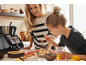 Mutter und Tochter dekorieren Blaubeer-Honig-Pfannkuchen, mit einer Küchenmaschine im Hintergrund.