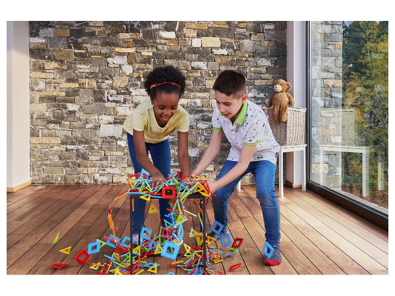 Zwei Kinder spielen mit bunten Bausteinen auf einem Holzboden.