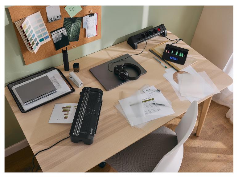 Schreibtisch mit TRONIC Laminiergerät, Steckdosenleiste, Akkuladegerät und Büromaterial.