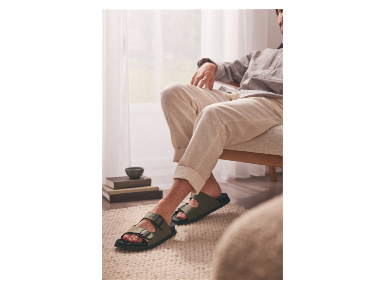 Ein Mann trägt grüne Birkenstock Sandalen.