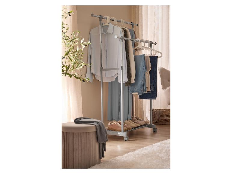 Ein mobiler Kleiderständer mit Kleidung, Schuhen und einem Hocker in einem Raum.