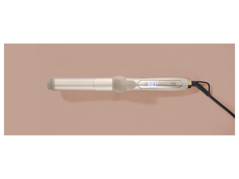 Goldener Lockenstab mit Digitalanzeige und schwarzem Kabel auf beigem Hintergrund.