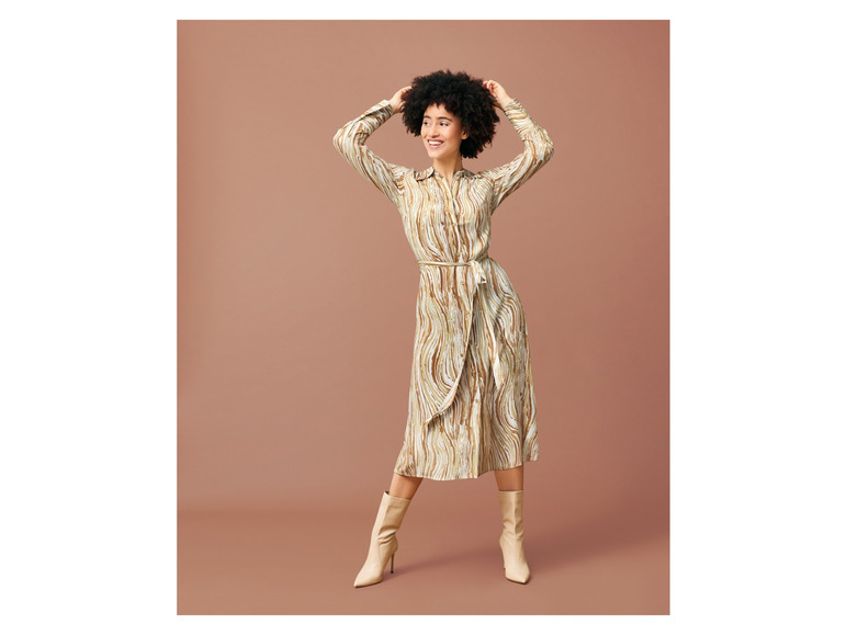 Eine Frau trägt ein gestreiftes Kleid und beige Stiefel.