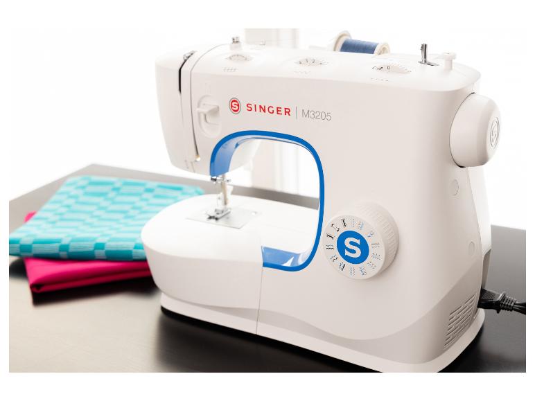 Weiße Nähmaschine mit blauen Akzenten, einer Spule blauen Fadens und bunten Stoffen