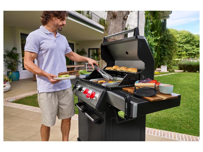 Mann grillt Burger auf einem Gasgrill im Garten.