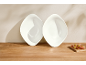 Zwei weiße ovale Servierschalen auf einem Holztisch mit Prosciutto und Oliven.