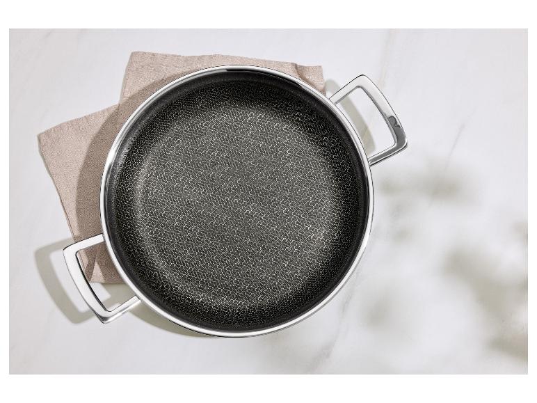 Bratpfanne mit Metallgriff auf einem Küchentuch auf einer weißen Marmoroberfläche