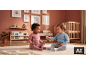 Zwei Babys spielen auf einem Teppich in einem Kinderzimmer mit Holzbett und Regalen.