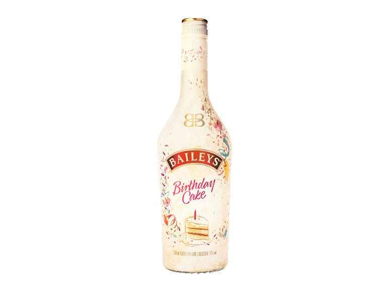 Flasche Sahnelikör mit Geburtstagskuchengeschmack, verziert mit Konfetti und einem Stück Kuchen.