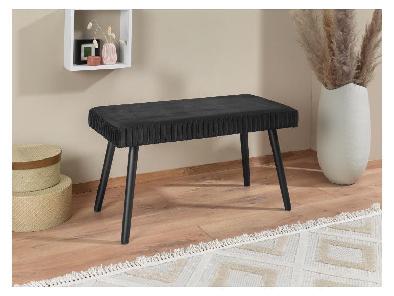 Eine schwarze Samtbank mit Holzbeinen in einem modernen Interieur.