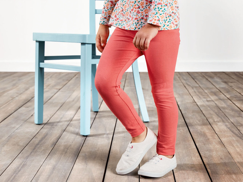 Ein Mädchen trägt eine rosa Hose und weiße Sneakers.