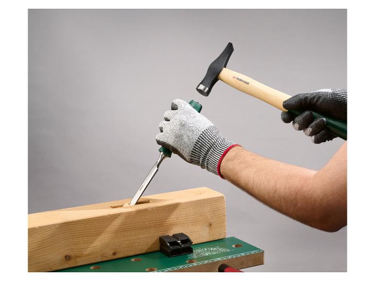 Behandschuhte Hände verwenden Meißel und Hammer, um einen Holzbalken zu bearbeiten.