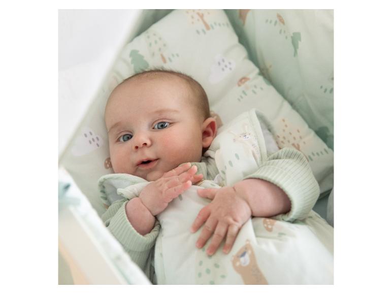 Baby in einem hellgrünen Schlafsack mit Tier- und Baumdruck.