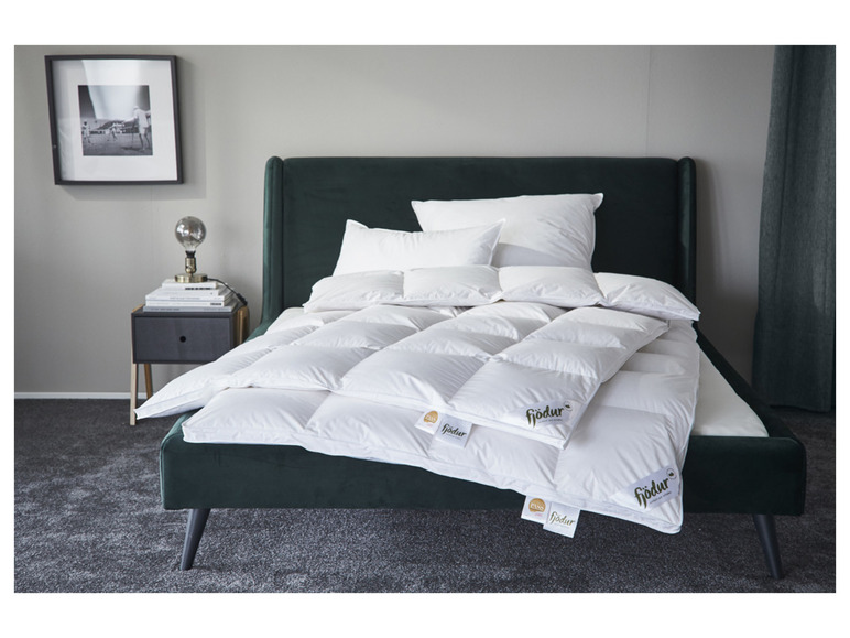 Ein grünes Samtbett mit einer Fjodur Bettdecke und Kissen.