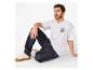 Mann in weißem T-Shirt mit Nummer 23 und dunkler Jeans, auf dem Boden sitzend.