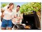Paar grillt im Freien, Frau hält ein Getränk und Mann wendet Essen auf dem Grill.