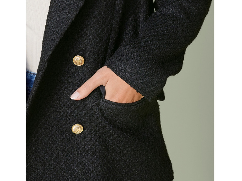 Ein schwarzer Blazer mit goldenen Knöpfen und einer Tasche.