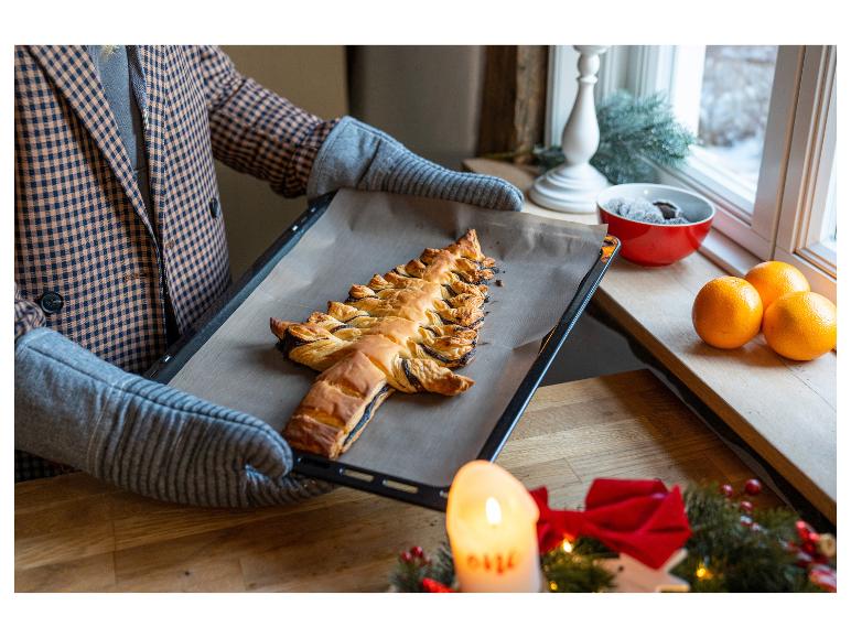 Eine Person hält ein Backblech mit einem Weihnachtsbaum-Gebäck.