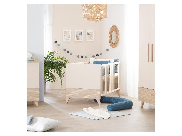 Ein Kinderzimmer mit Babybett, Kommode und Kleiderschrank in hellen Farben.