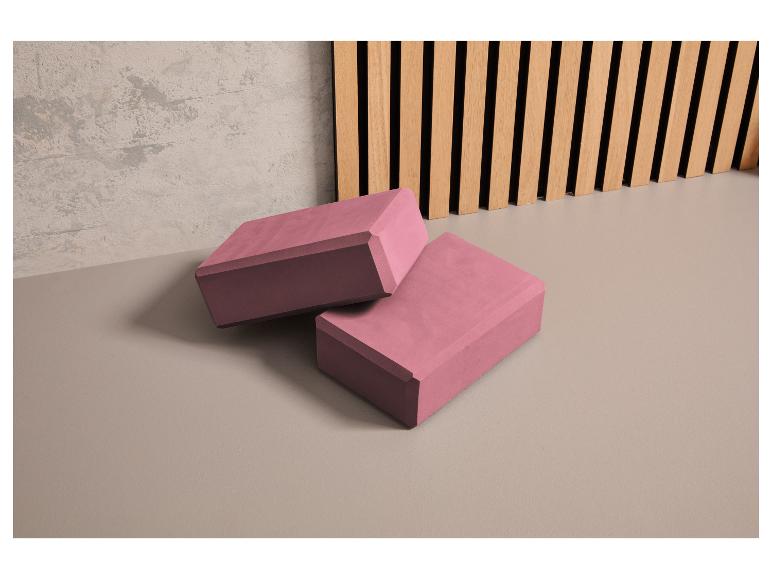 Zwei rosa Yogablöcke auf einem grauen Boden.