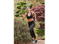 Eine Frau in schwarzem Sport-BH und Leggings joggt durch einen Park.