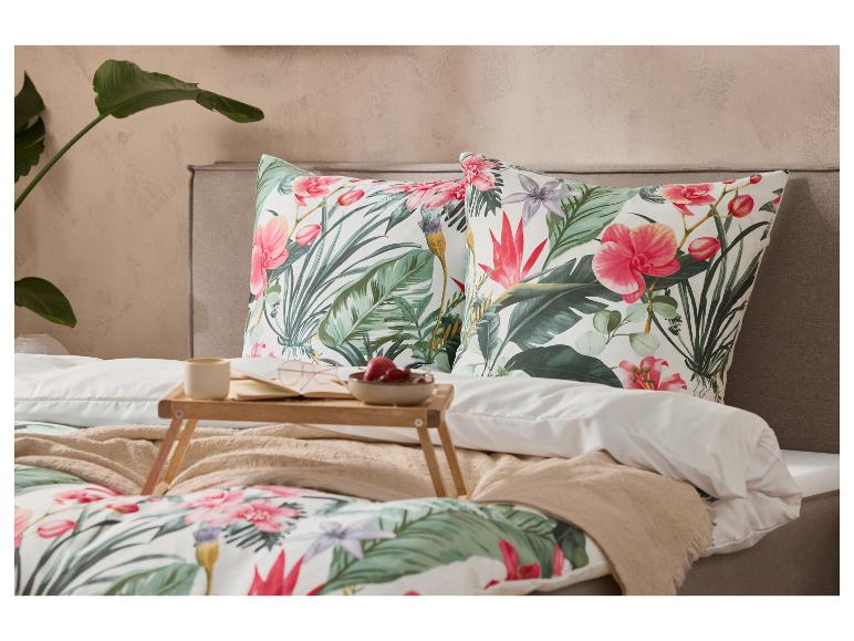 Bett mit tropischer Blumenbettwäsche und Kissen, ein Frühstückstablett mit Kaffee und Obst.