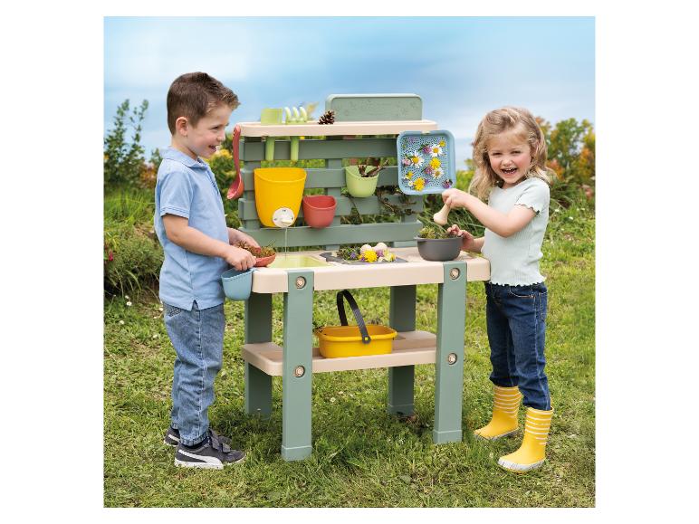 Zwei Kinder spielen draußen mit einem Smoby Spiel-Gartentisch.