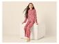 Mädchen in rosa Pyjama mit schwarzen Herzen, sitzt auf einem weißen Pouf.
