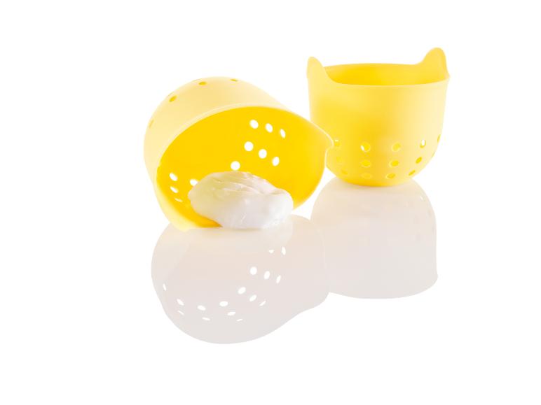 Zwei gelbe Eierhalter mit einem Ei in einem von ihnen.