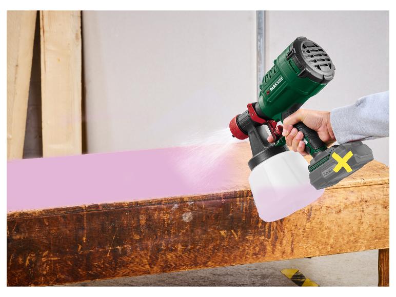 Akku-Farbspritzpistole sprüht rosa Farbe auf einen Holztisch.