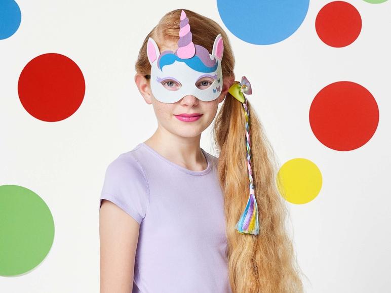 Ein Mädchen trägt eine Einhornmaske mit einem Regenbogenhaarband.