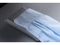 Hellblaue Hemdmanschette mit Knöpfen und Falten, auf grauem Stoff liegend.