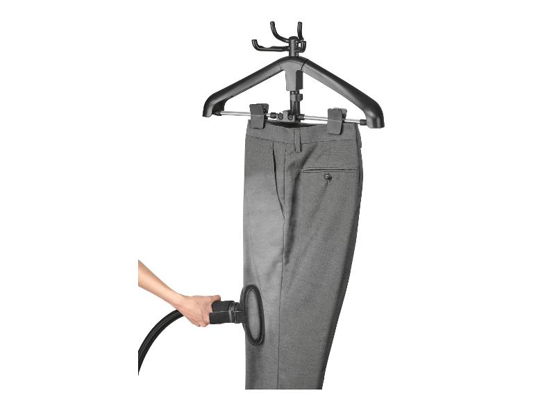 Graue Hose auf einem Kleiderbügel, die mit einem Handdampfglätter gedämpft wird.