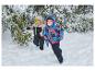 Zwei glückliche Kinder in warmer Winterkleidung und Schneestiefeln spielen im Schnee.