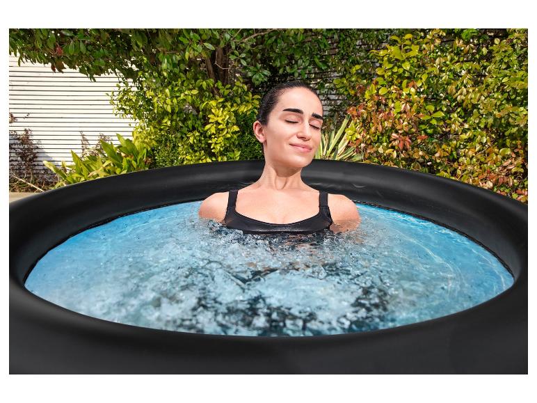 Frau entspannt sich in einem Outdoor-Whirlpool, umgeben von Grün.