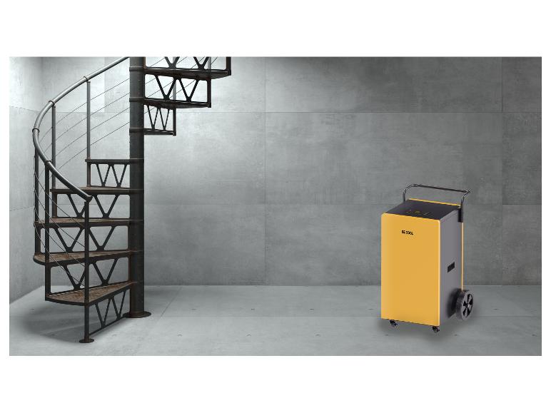 Ein gelb-schwarzer tragbarer Luftentfeuchter in einem Industrieraum mit Wendeltreppe.