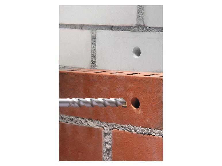 Bohren in eine Ziegelwand mit einem Bohrer, darüber ein weißer Ziegel mit Loch.