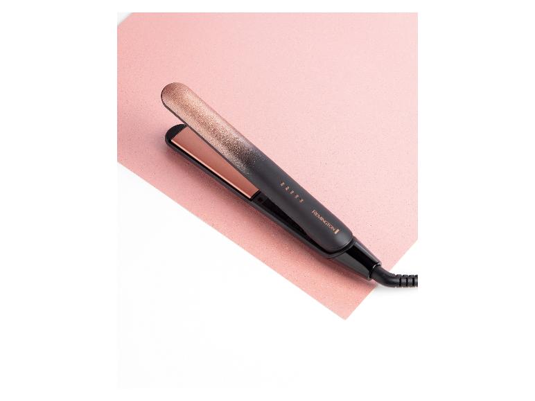 Schwarzer und roségoldener Haarglätter auf rosa Hintergrund.