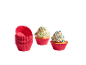 Zwei Cupcakes mit Streuseln und ein Stapel roter Silikon-Muffin-Förmchen.