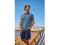Mann in blauem Poloshirt und blauen Cargoshorts am Strand mit Liegestuhl.