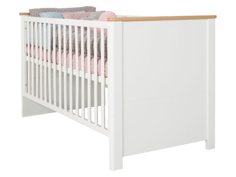 Ein weißes Babybett mit rosa und grauer Bettwäsche