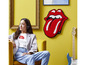 Eine Frau hört mit Kopfhörern Musik, während an der Wand ein LEGO® Kunstwerk der Rolling Stones hängt.