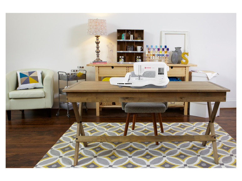 Eine Singer Legacy Nähmaschine auf einem Holztisch mit Stuhl und Teppich.
