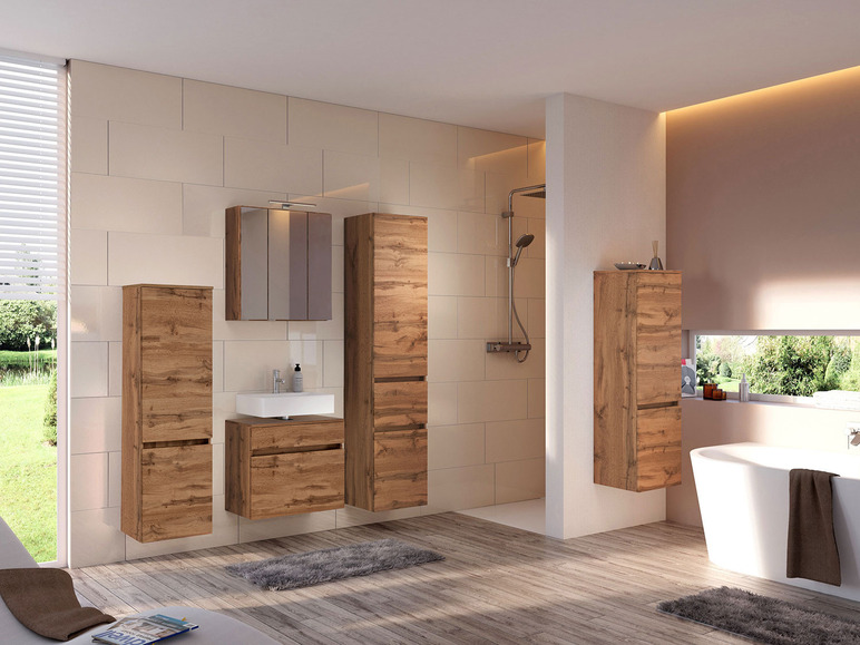 Badezimmer mit Holz-Badmöbeln, einem Spiegelschrank und einer Badewanne.