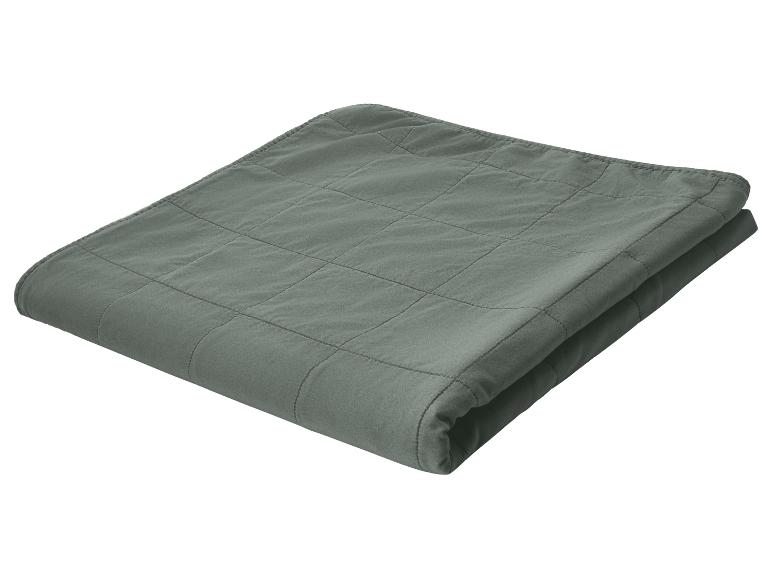 Gefaltete dunkelgrüne Steppdecke mit Karomuster.