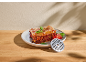 Lasagne mit Basilikum und Tomaten, mit einer Fleischwolfscheibe auf einem Holztisch.