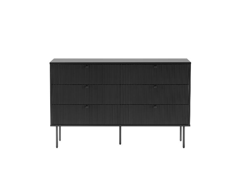 Schwarze Kommode mit drei Schubladen und geriffelten Fronten auf dünnen Metallbeinen.