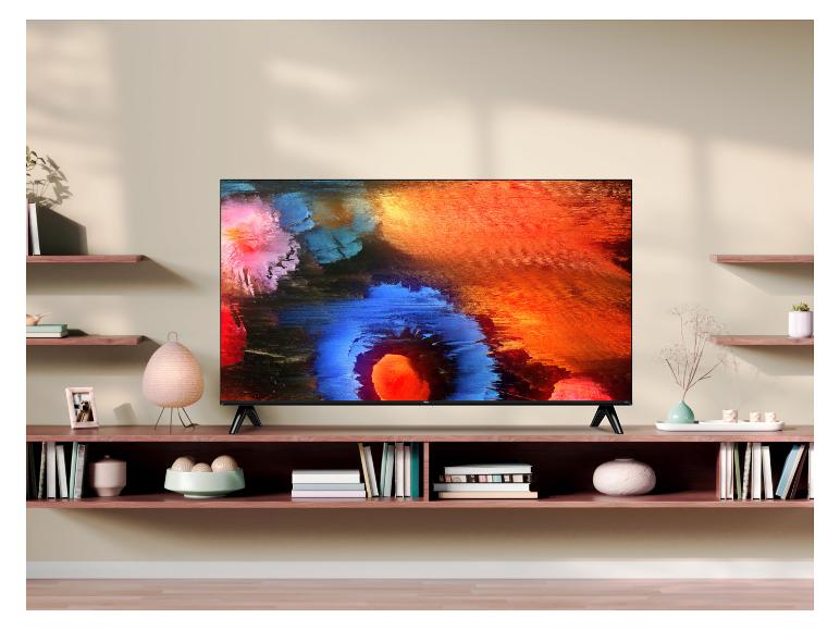 Großer Fernseher auf einem Schrank mit Regalen und Dekoration.