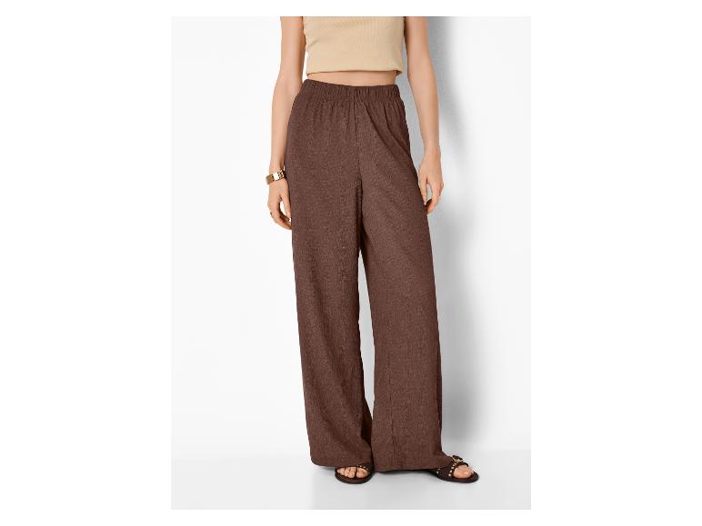 Frau in hellem Top und brauner weiter Hose mit Sandalen.